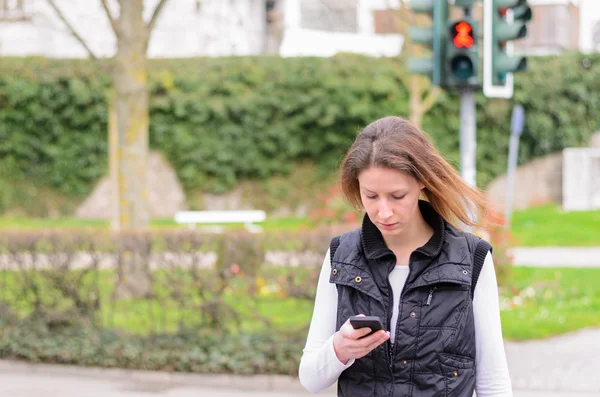 Alleenstaande vrouw lopen en kijken neer op telefoon — Stockfoto