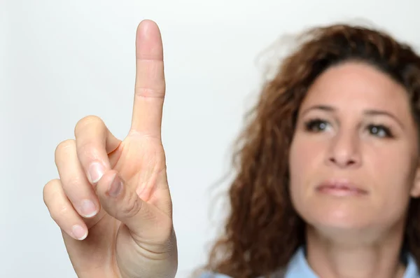 Woman reaching with a finger to touch a screen — Stockfoto