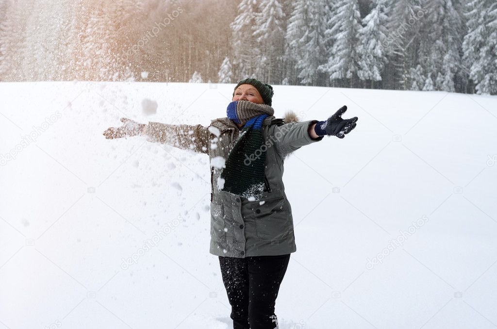 Happy senior woman playing in the snow
