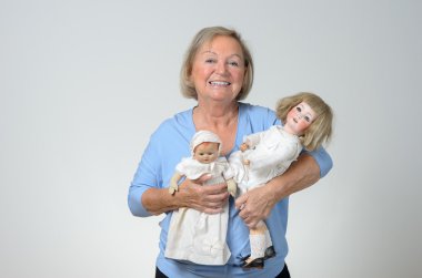 Elderly woman holding two antique dolls clipart