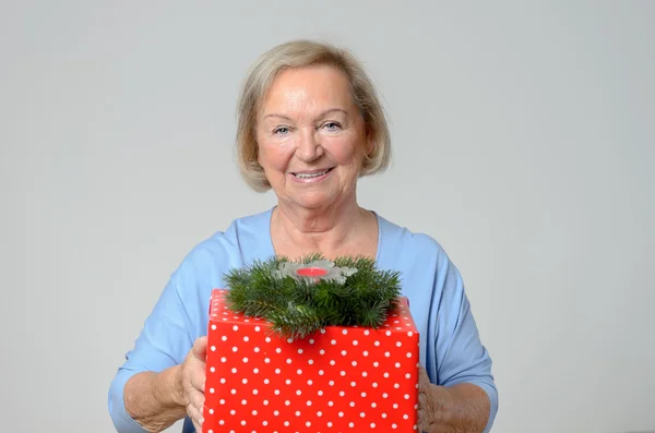 Attractive elderly lady with a large Xmas gift — Stock Photo, Image