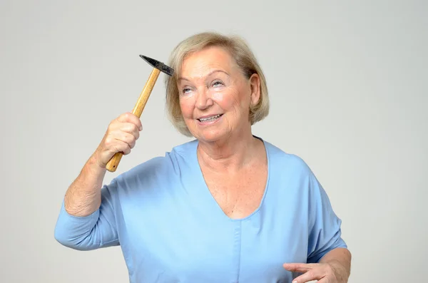 Elderly lady hitting her head with a hammer — Stock Photo, Image