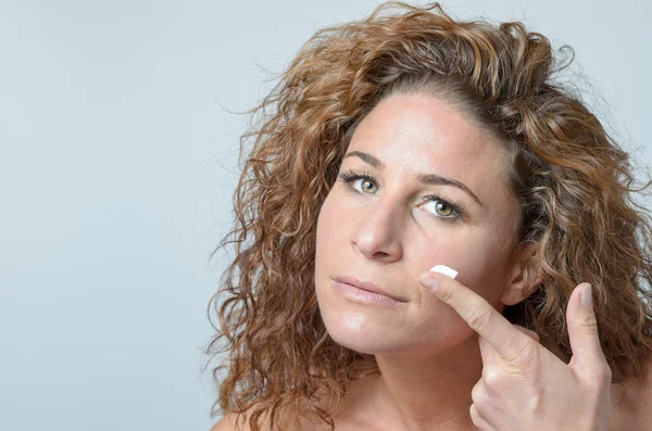 Mujer aplicando crema hidratante a su piel — Foto de Stock