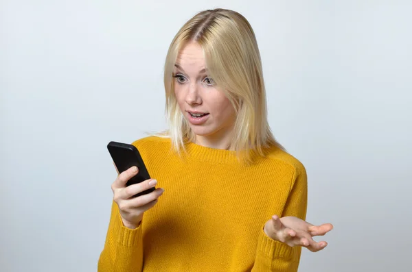 Überraschte junge Frau schaut auf ihr Handy — Stockfoto