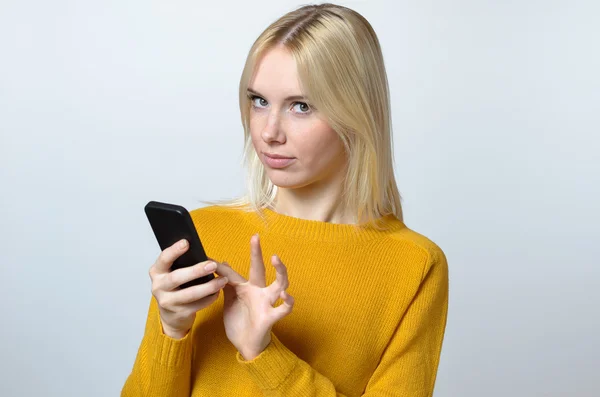 Junge Frau blickt mit ihrem Handy in die Kamera — Stockfoto
