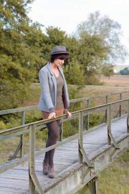 Bir yaya köprüsü üzerinde düşünceli trendy genç kadın