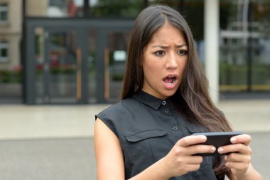 Young woman reacting in horror to an sms