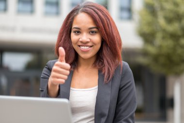 Young Student with Laptop Showing Thumbs up
