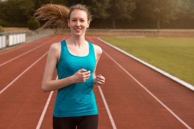 Young woman runner training on a track clipart
