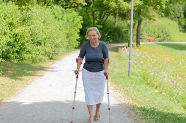 Yaşlı bayan ülkede koltuk değneği üzerinde yürüme
