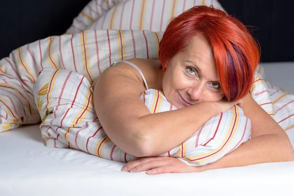 Счастливая женщина средних лет, лежащая в кровати . — стоковое фото