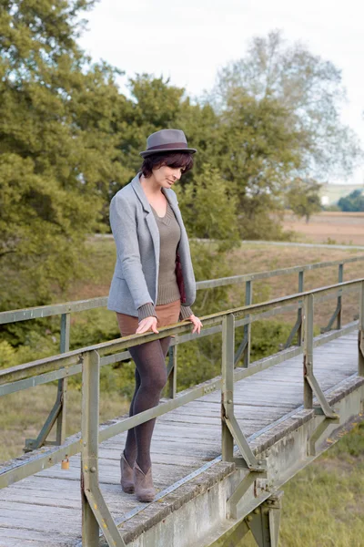 Bir yaya köprüsü üzerinde düşünceli trendy genç kadın