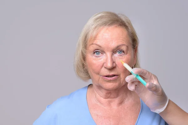 Косметическая инъекция на лице пожилой женщины — стоковое фото