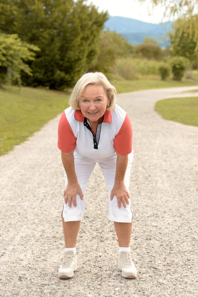 Atletische oudere vrouw trainen op een landelijke weg — Stockfoto