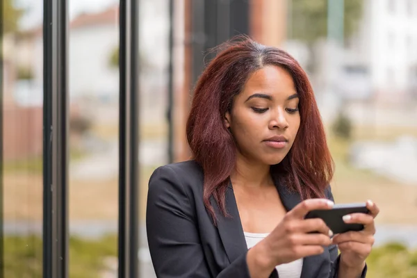 Mujer de Oficina Afroamericana Mensajes de texto en su teléfono — Foto de Stock