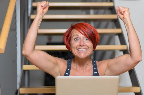 Mulher adulta feliz com laptop levantando seus braços — Fotografia de Stock