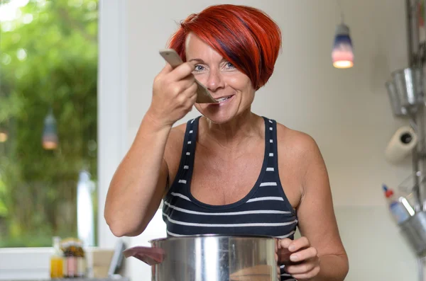 Mujer adulta degustando su receta con cucharón de madera —  Fotos de Stock