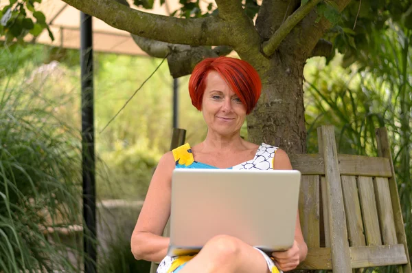 Mulher adulta com laptop sentado sob a árvore — Fotografia de Stock