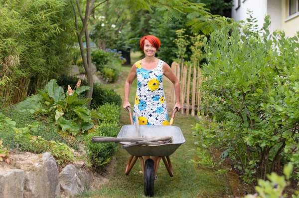 幸福的女人推着独轮车的工具 — 图库照片