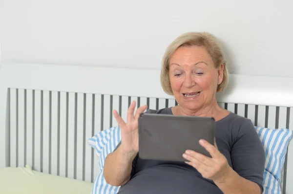 Elderly woman using a tablet-pc in bed