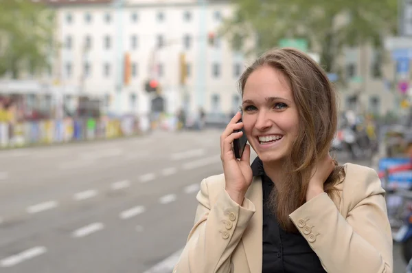 Mujer joven riendo mientras charla en su móvil — Foto de Stock