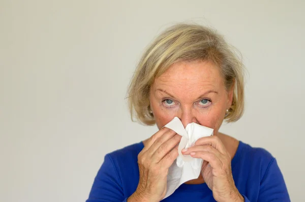 Elderly woman blowing her nose — Stock Photo, Image