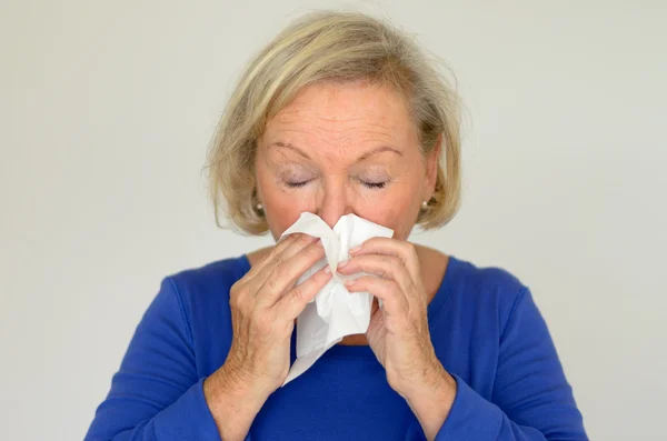 Elderly woman blowing her nose — Stock Photo, Image