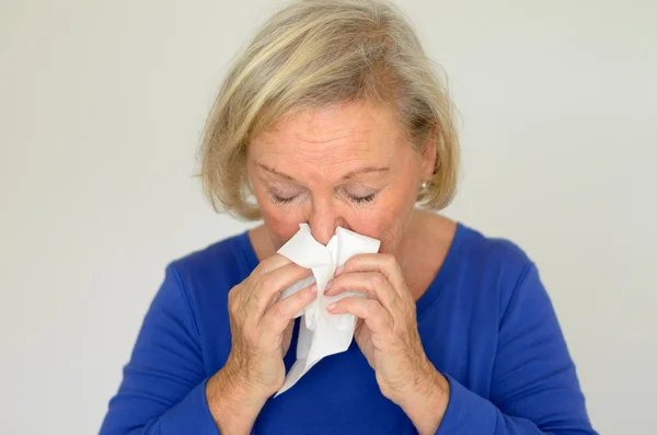 Elderly woman blowing her nose — Stock Photo, Image