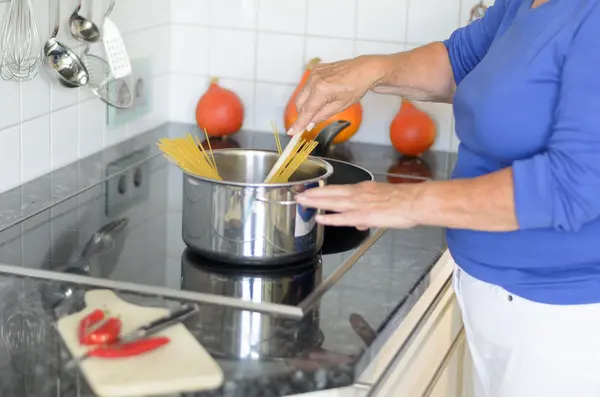 Lady cocinando pasta de espaguetis en su estufa —  Fotos de Stock