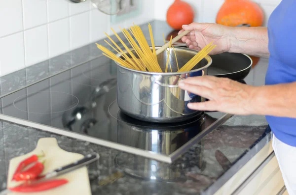 Lady cocinando pasta de espaguetis en su estufa —  Fotos de Stock