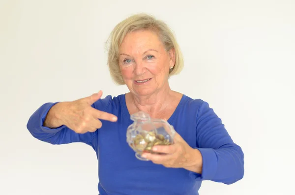 Smiling senior woman holding a glass piggy bank — Stock Photo, Image