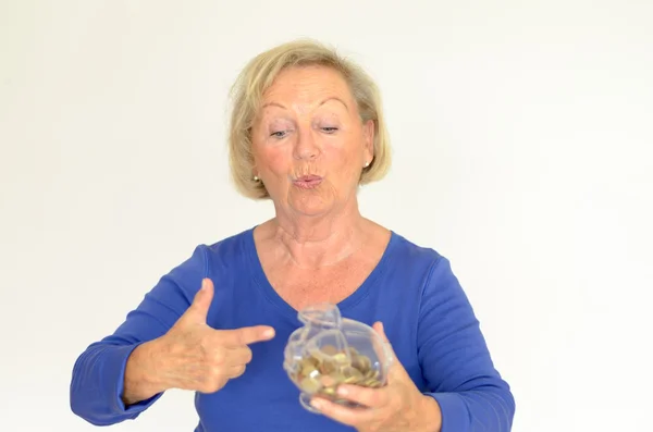 Smiling senior woman holding a glass piggy bank — Stock Photo, Image