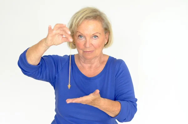 Woman holding a pendulum over her hand — Stock Photo, Image