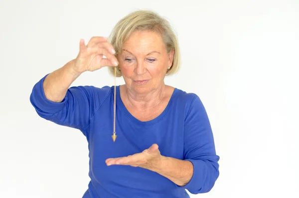 Woman holding a pendulum over her hand — Stock Photo, Image