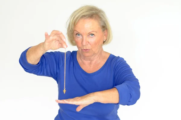 Woman holding a pendulum over her hand — Stock Photo, Image