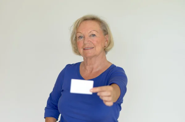 Elderly lady holding out a blank card — Stock Photo, Image