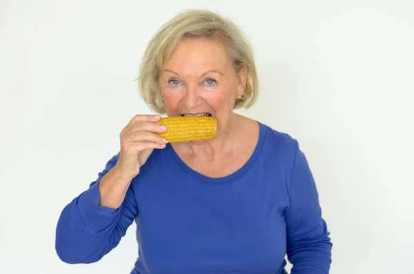 Пожилая дама наслаждается свежей кукурузой в початках — стоковое фото