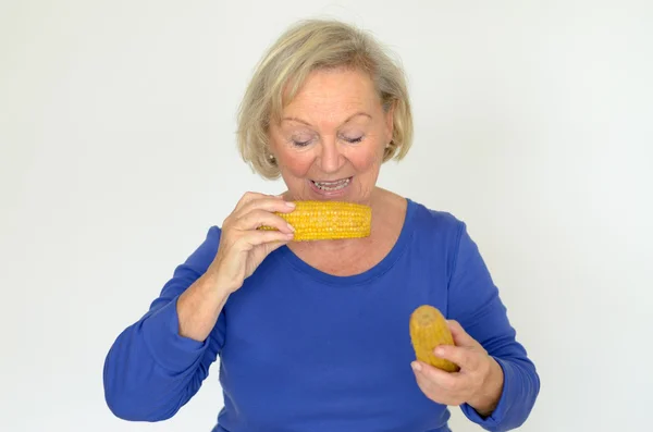 Elderly lady enjoying fresh corn on the cob — Stock Photo, Image