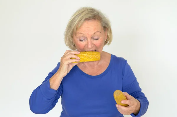 Elderly lady enjoying fresh corn on the cob — Stock Photo, Image