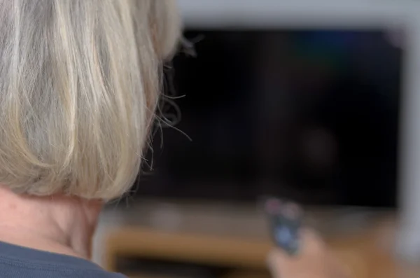 Mujer adulta cabelludo blanco sosteniendo TV control remoto — Foto de Stock