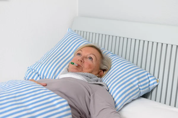 Mujer enferma acostada en la cama con termómetro en la boca — Foto de Stock