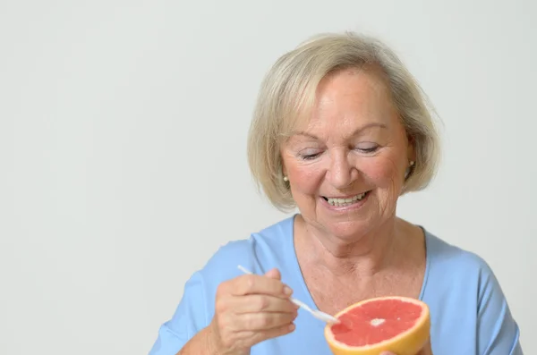 Happy healthy senior lady with a red grapefruit — Stock Photo, Image