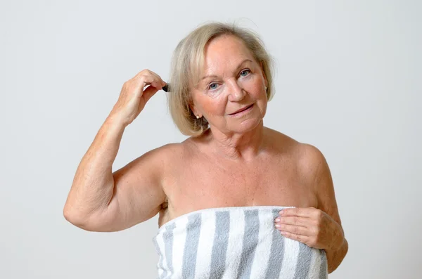 Старшая женщина расчесывает волосы — стоковое фото