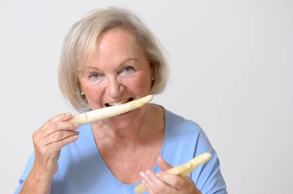 Happy healthy senior lady with a white asparagus — Stock Photo, Image