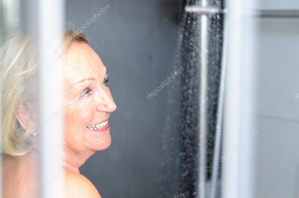 Smiling attractive senior woman taking a shower