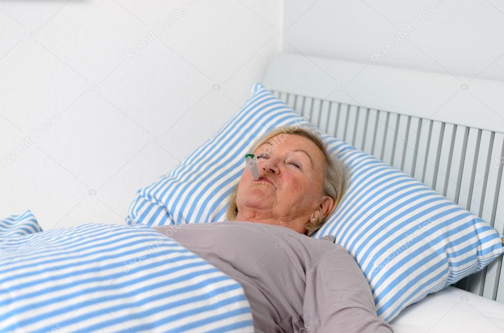 Sick Woman Lying on Bed with Thermometer in Mouth