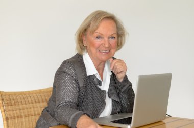 İş kadın kıdemli bak gümüş bir dizüstü bilgisayar önünde