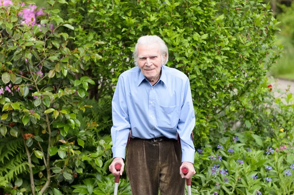 Elderly man using forearm crutches to walk — Stock Photo, Image