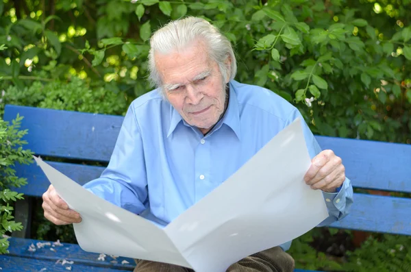 Elderly man sitting alone on a bench in the park — Stock Photo, Image