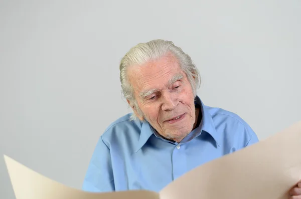 Elderly man holding a blank big ocher paper sheet — Stock Photo, Image
